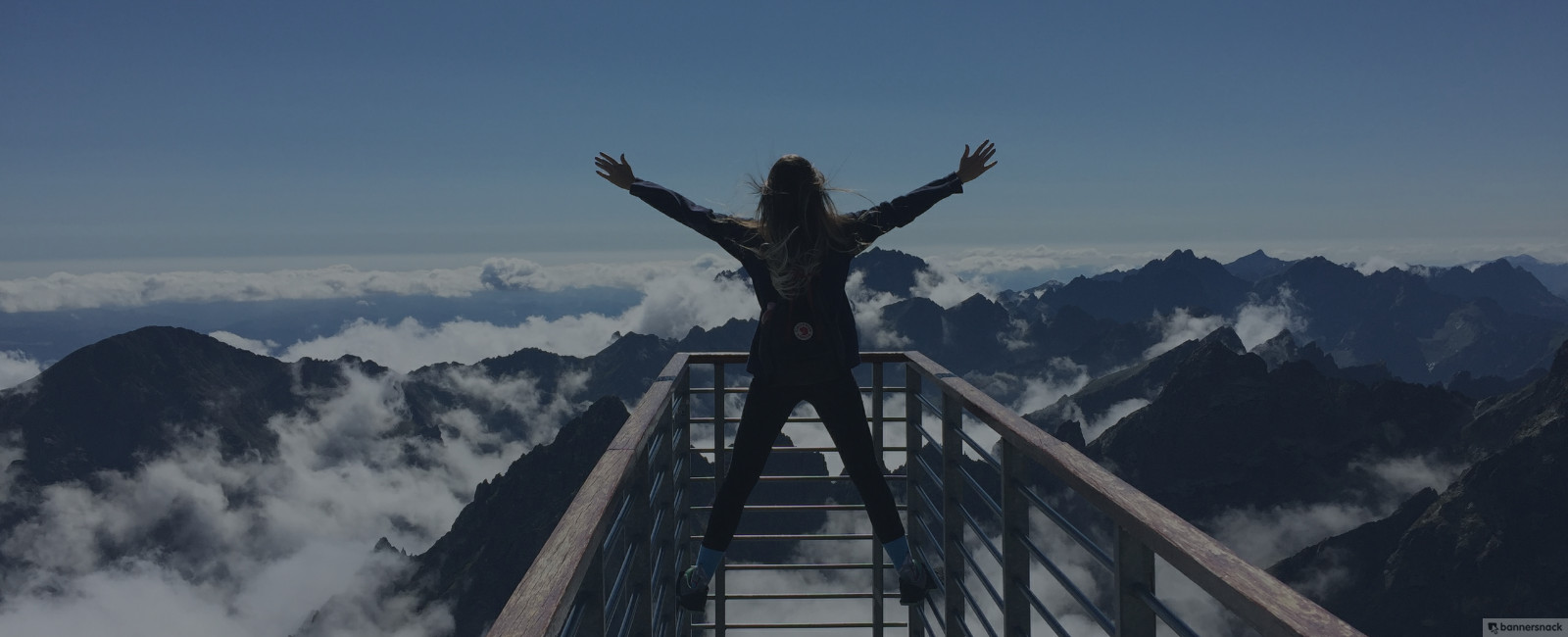 Person standing with arms wide open facing the mountains