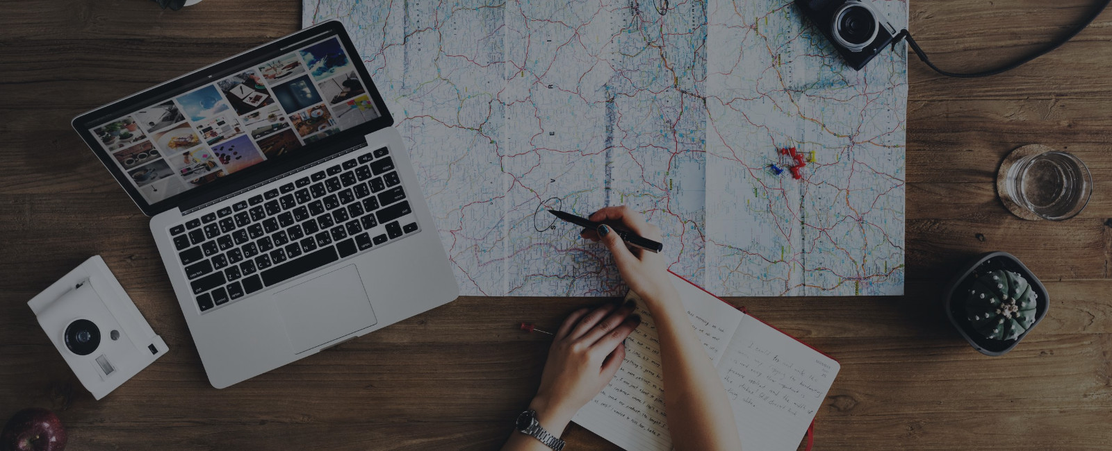 person next to a laptop marking on a map