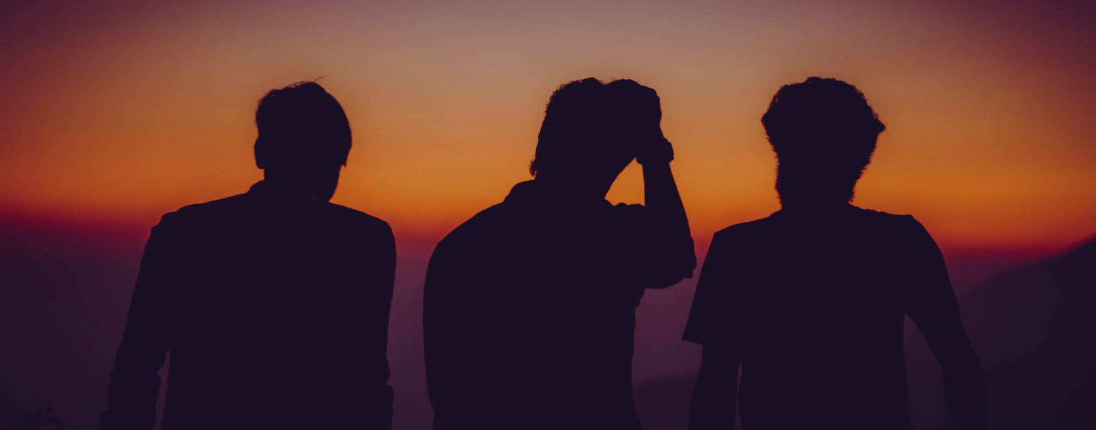 silhouette of 3 men watching sunset